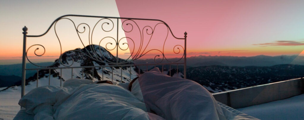 Ein Bett, dass draußen steht, mit Blick auf Berge und einen Sonnenuntergang